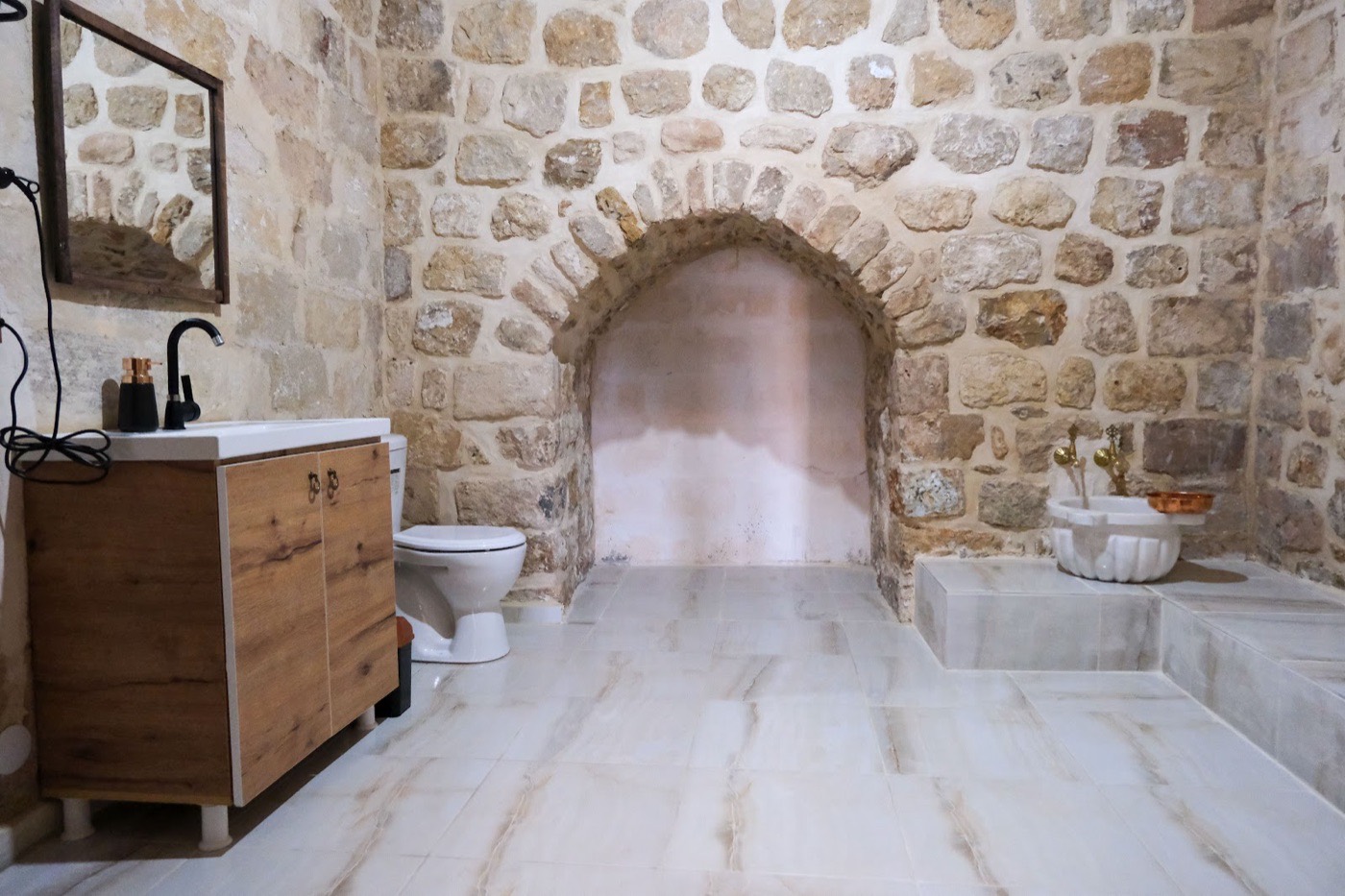 Taş kemerli, mermer zeminli geniş banyo